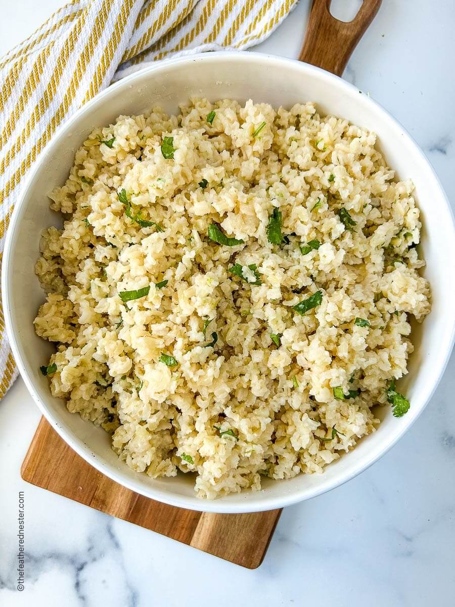 large white bowl filled with brown rice dish on a wooden board