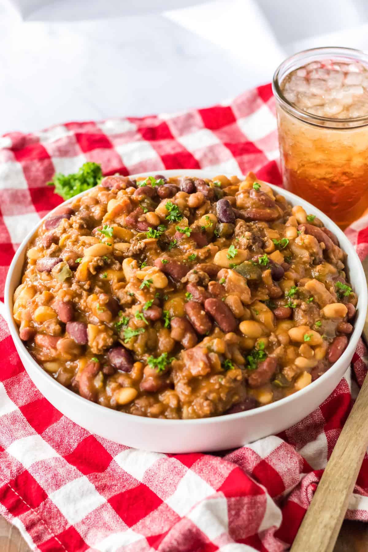 white bowl with cowboy beans sitting on red checkered cloth