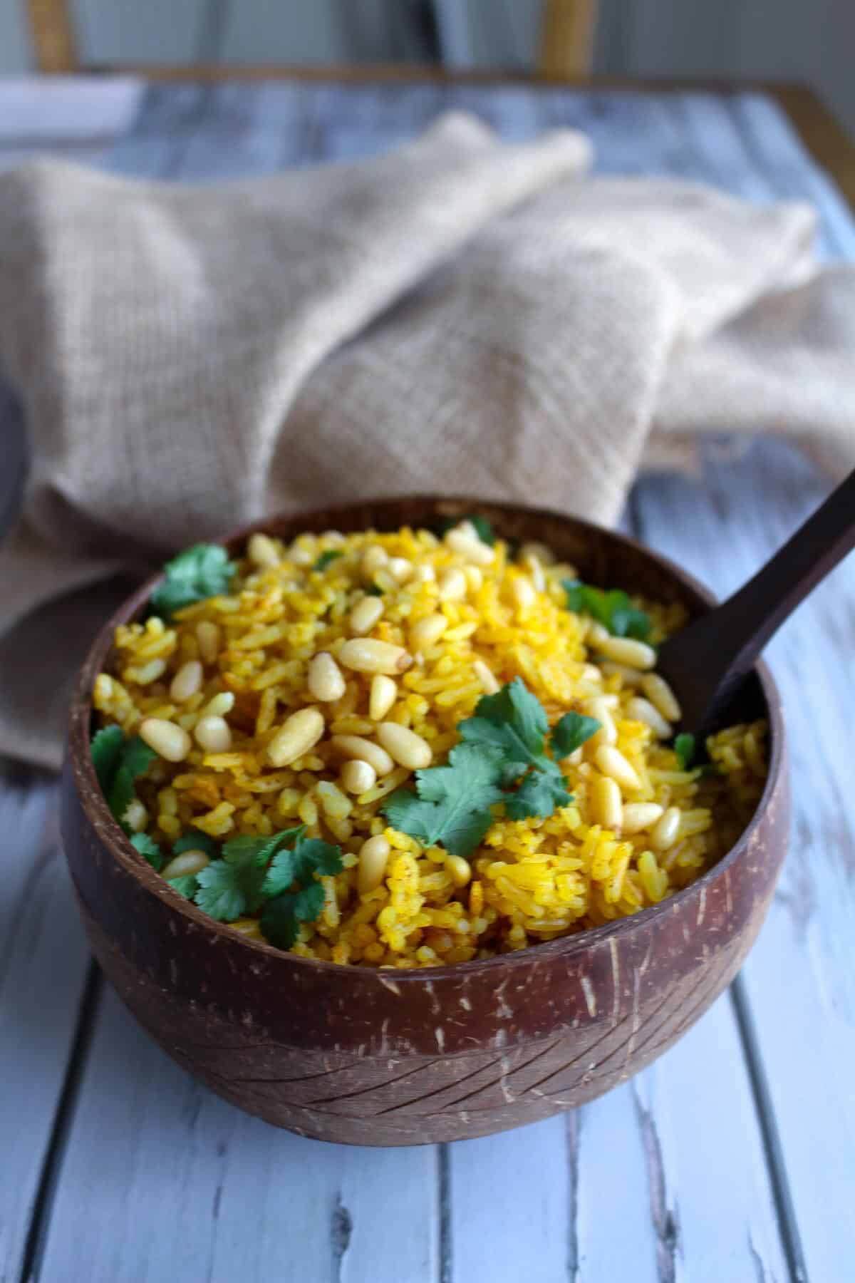 yellow rice in a dark coloured bowl on a blue wooden table