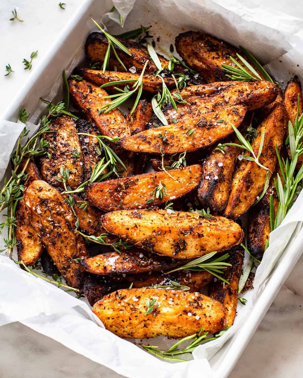 large white baking dish lined with baking paper with grilled potato wedges