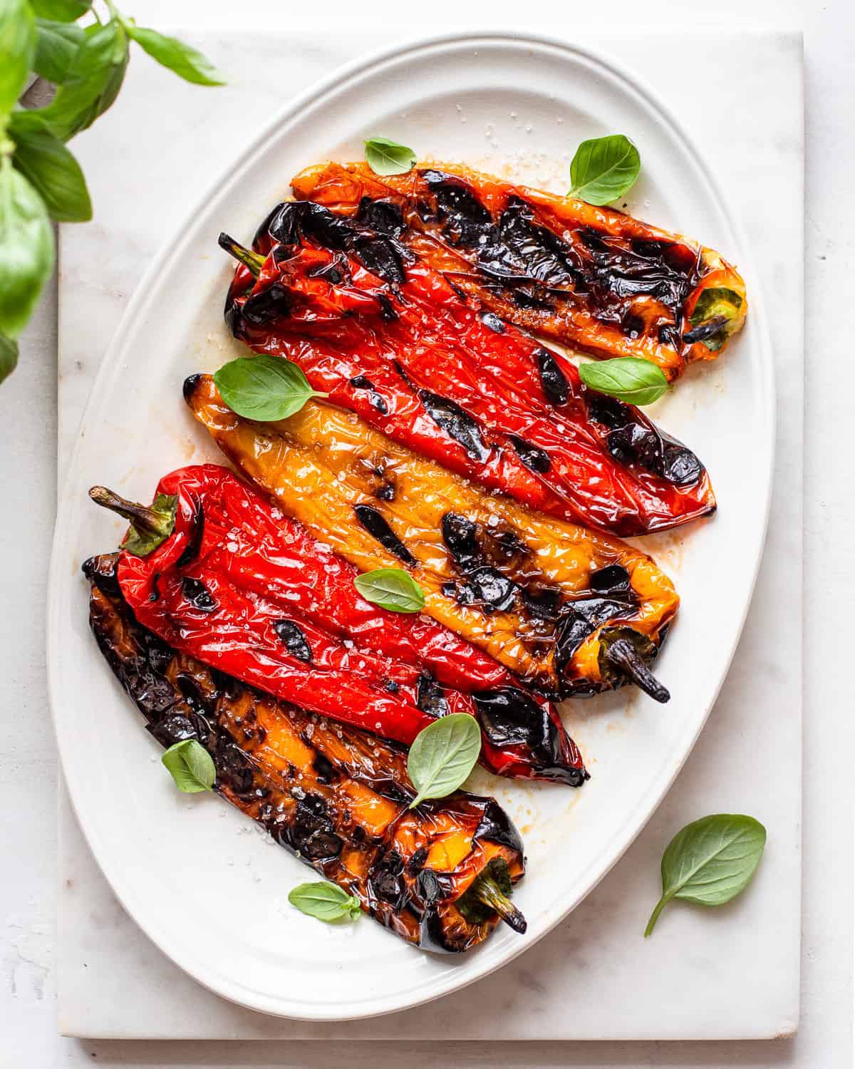 large white oval platter with grilled sweet peppers laid out