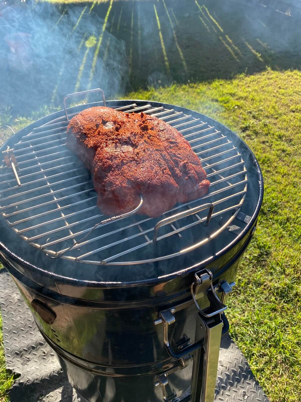 pork collar butt with meat rub on a bullet smoker outdoors