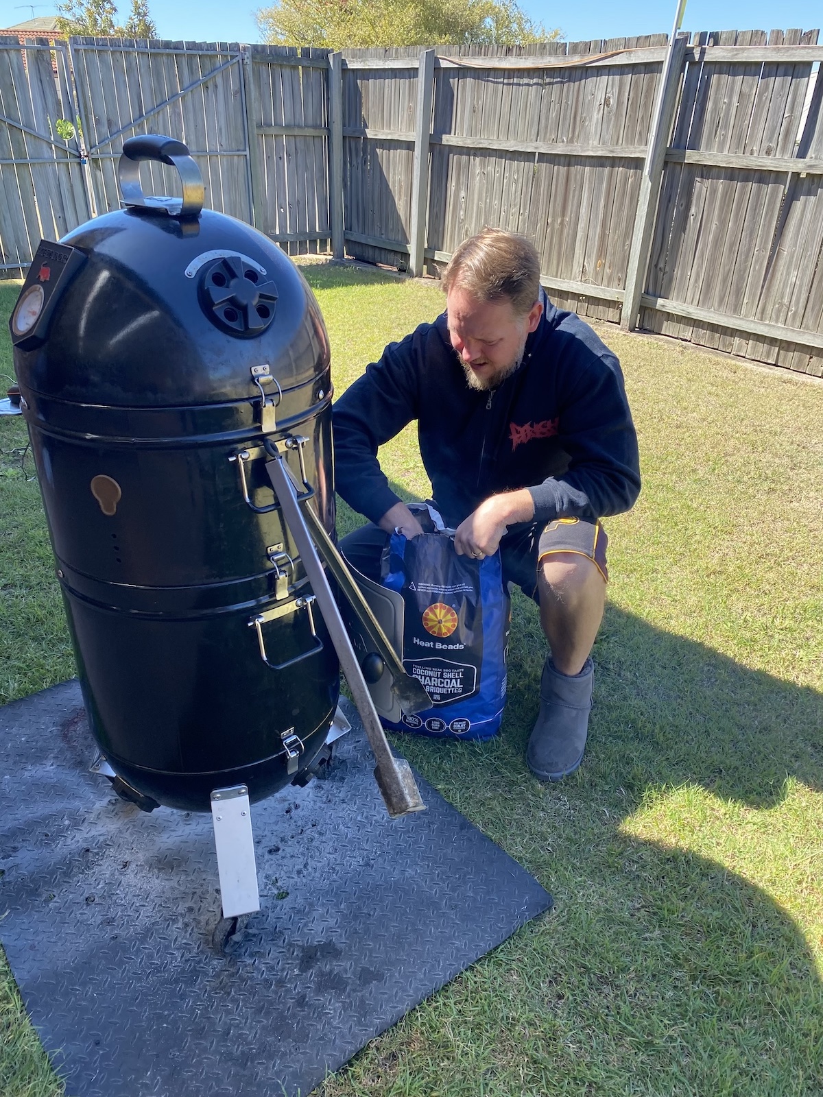 Simon adding charcoal to the bullet smoker in the backyard