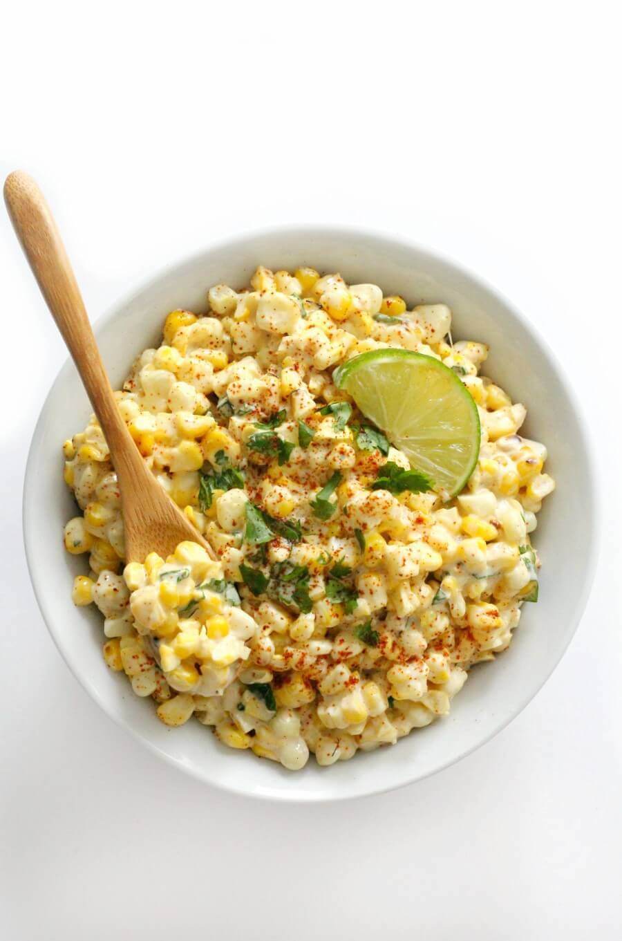 mexican street corn in a white bowl with a spoon sticking out