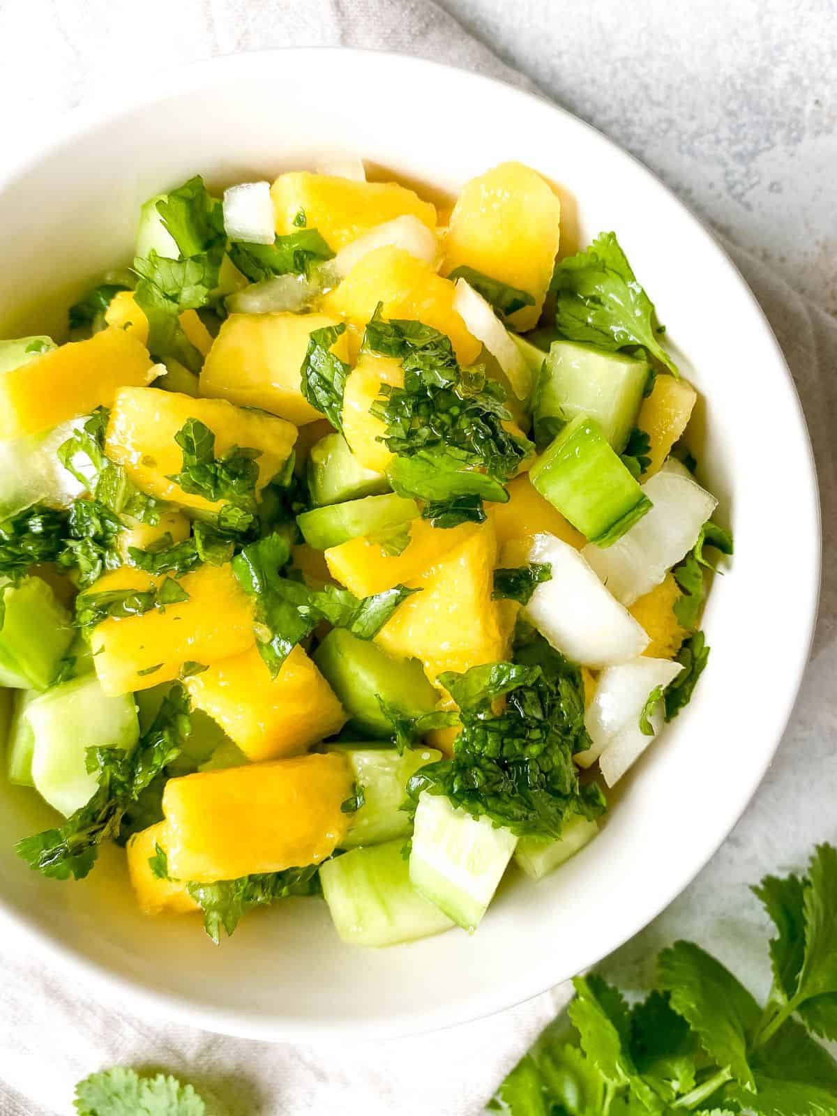 white bowl with mango cucumber salad ready to eat