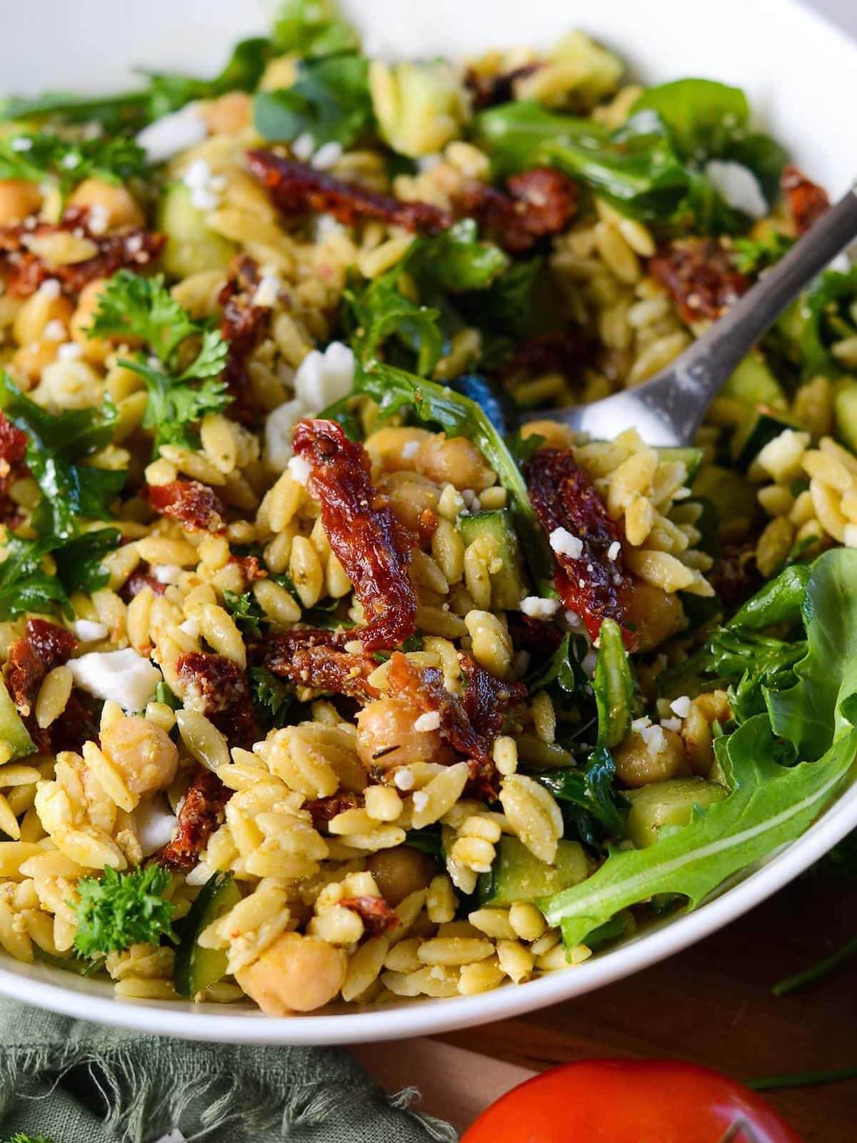 large serving bowl with pesto orzo salad and sundried tomatoes