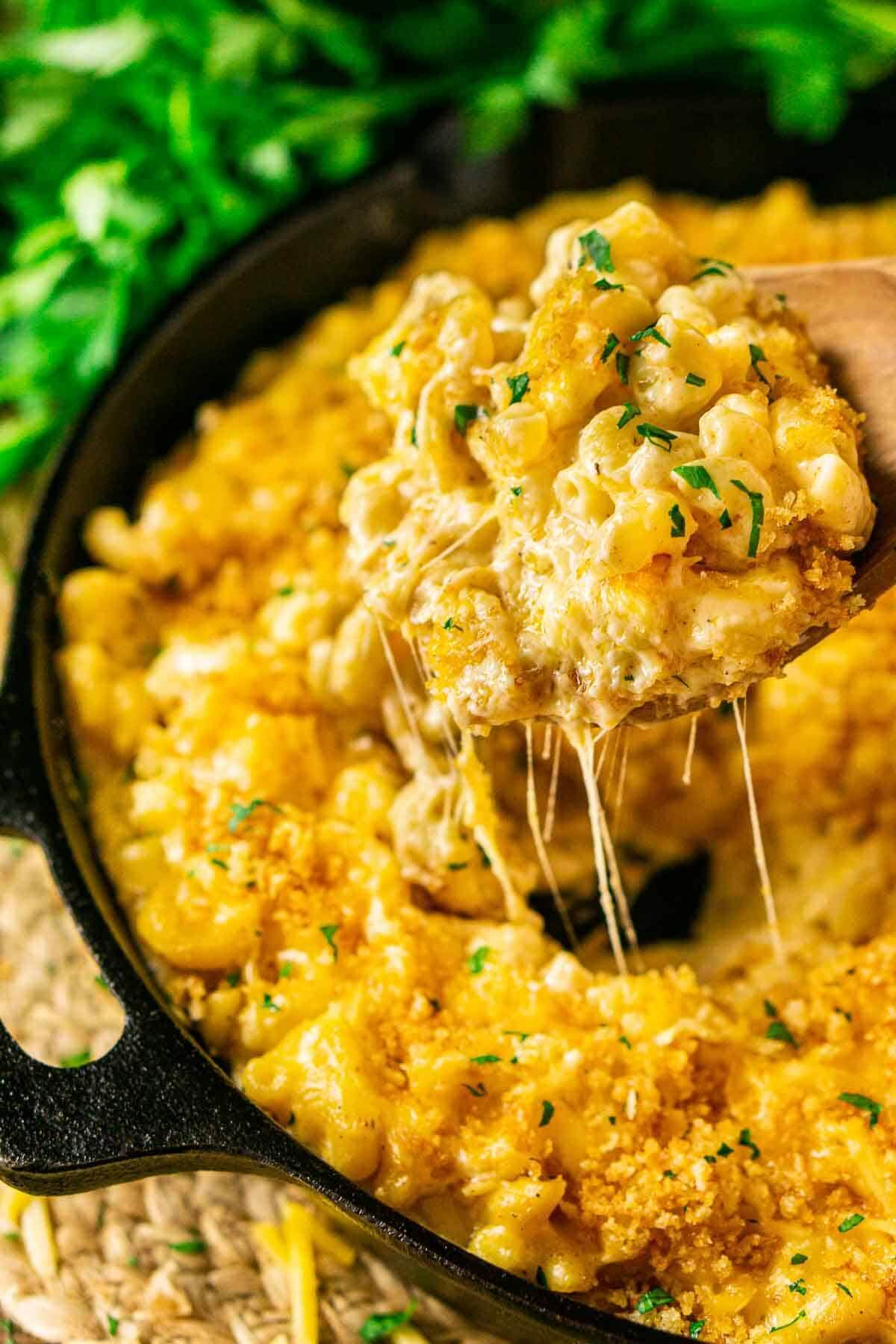 large skillet filled with mac and cheese with a spoon lifting up a portion