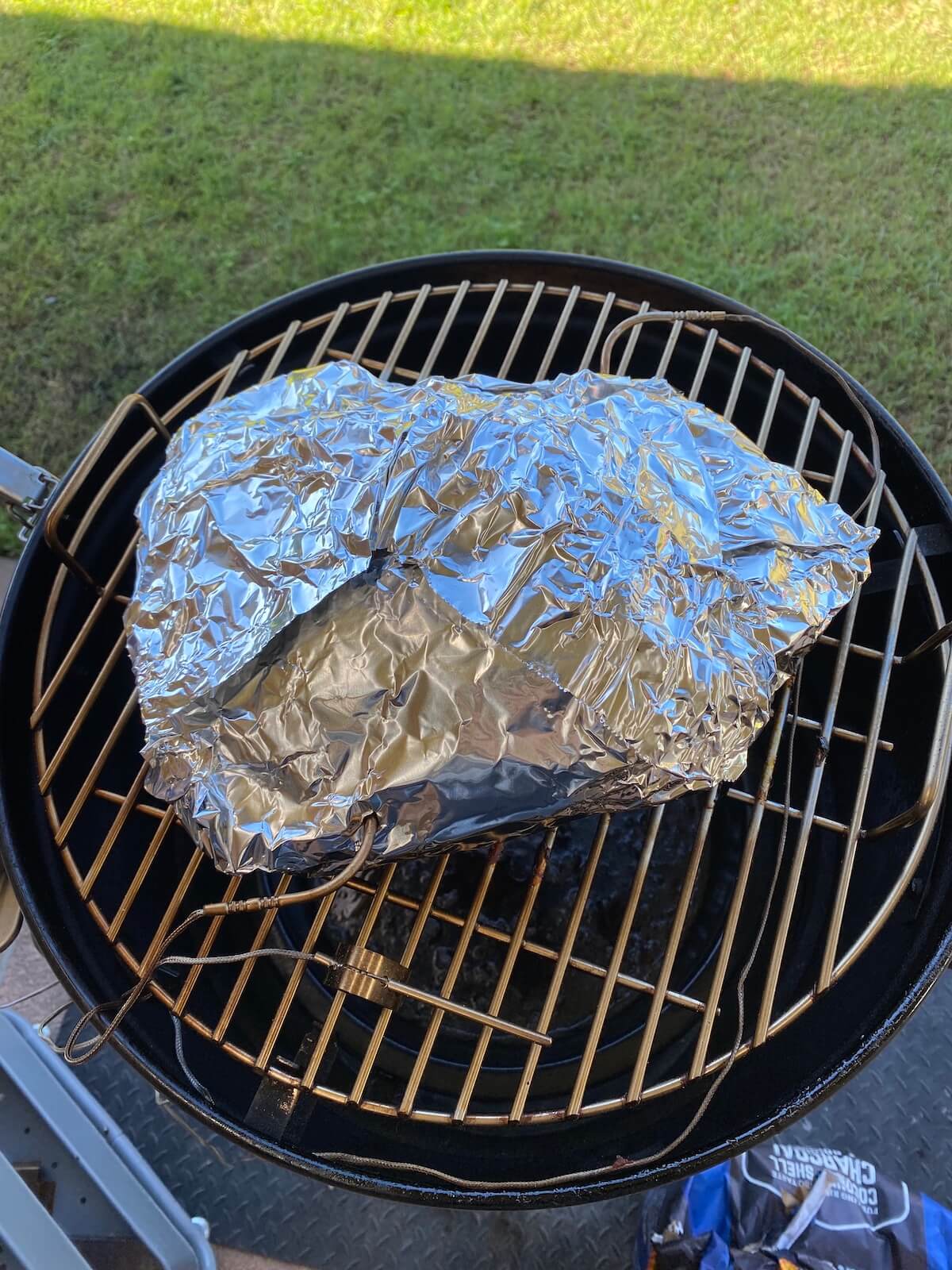 foil wrapped meat on top of the smoking grill