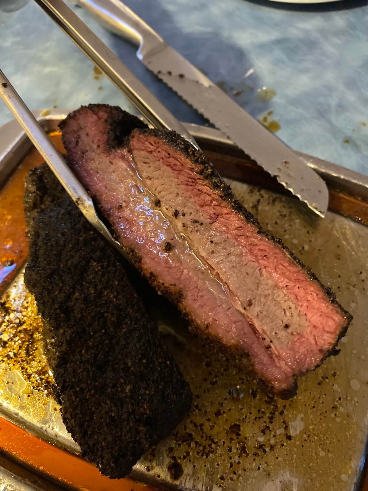 sliced brisket sitting in meat juices on carving tray.