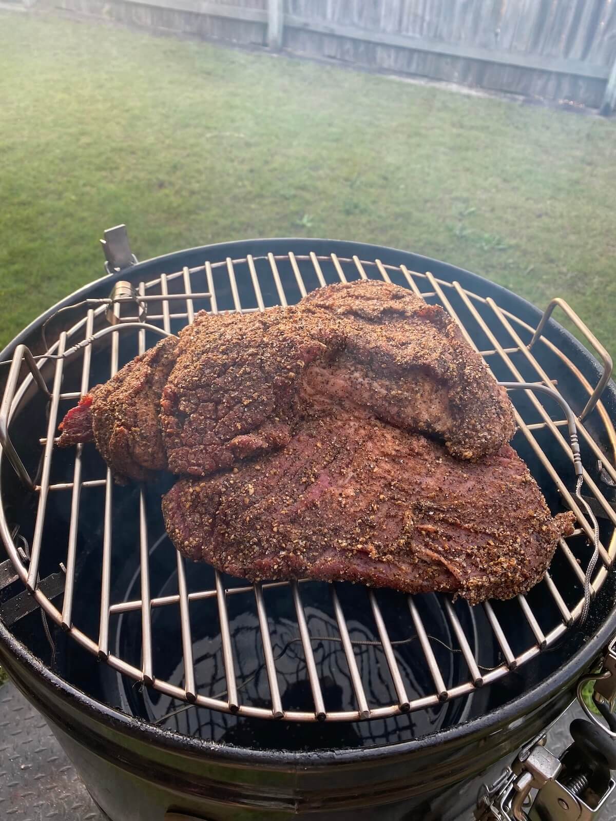 brisket on bullet smoker in backyard.