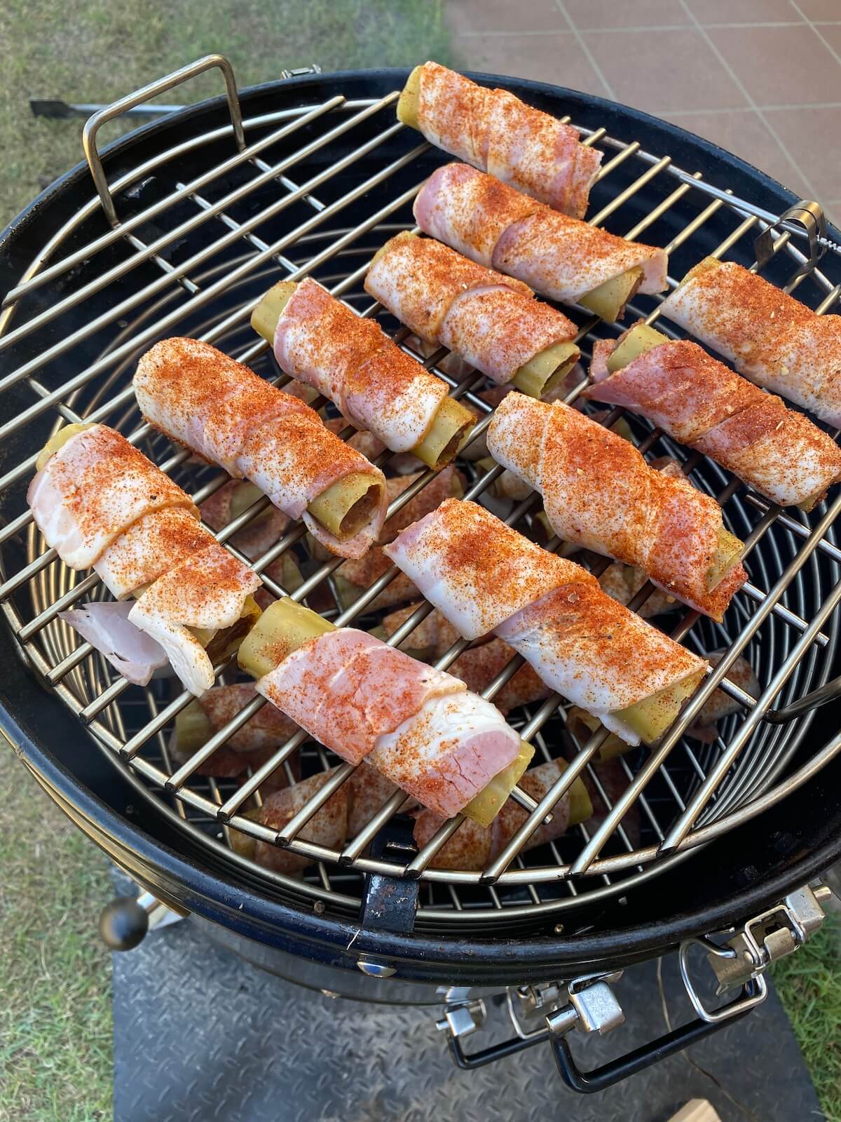 bacon wrapped stuffed cannelloni shells on a smoker grill grate.