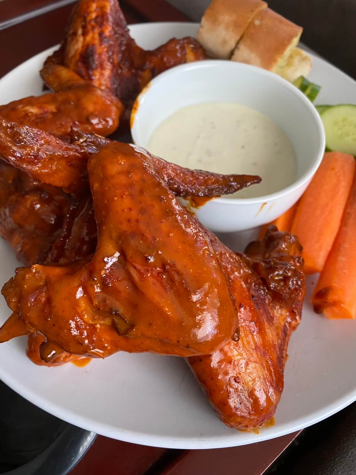 smoked buffalo wings with blue cheese sauce and carrot sticks on a plate.