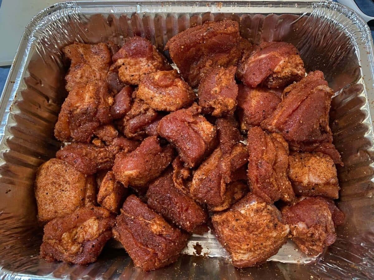 pork belly burnt ends with pork dry rub seasoning in foil tray.