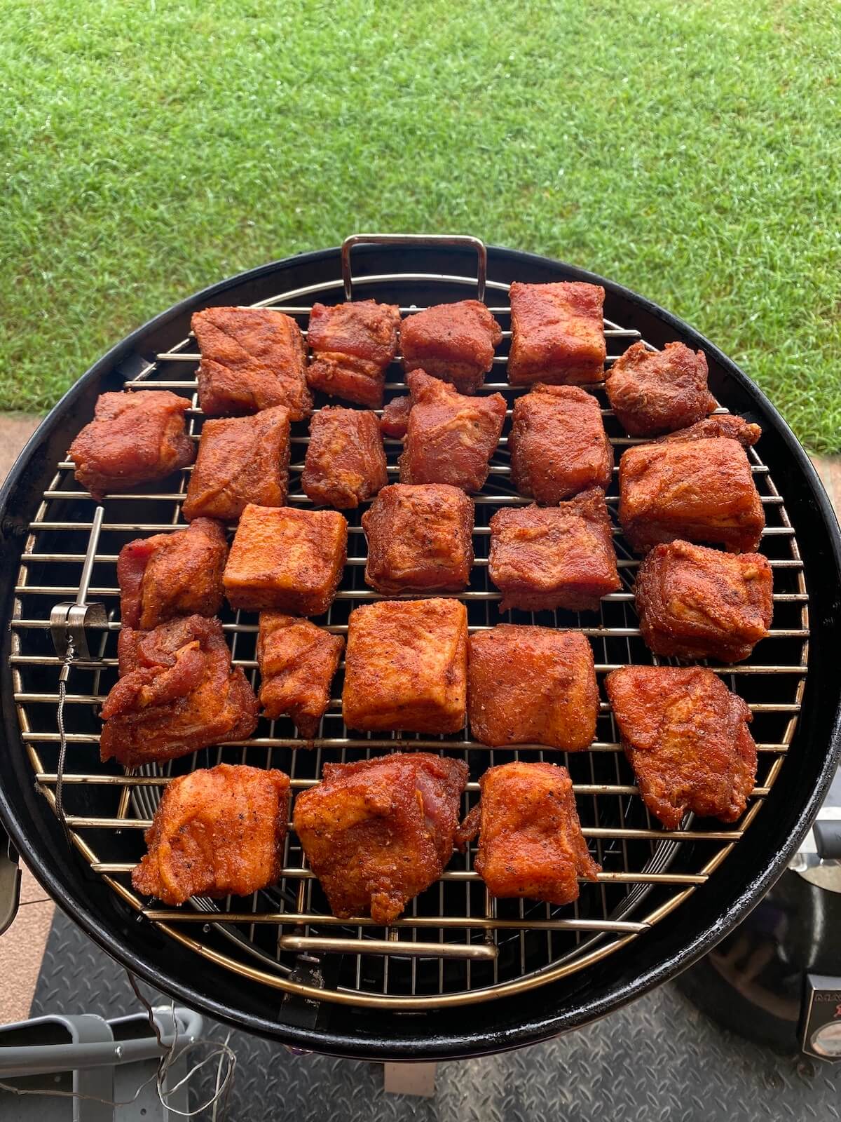 pork belly burnt ends cooking on a smoker rack.