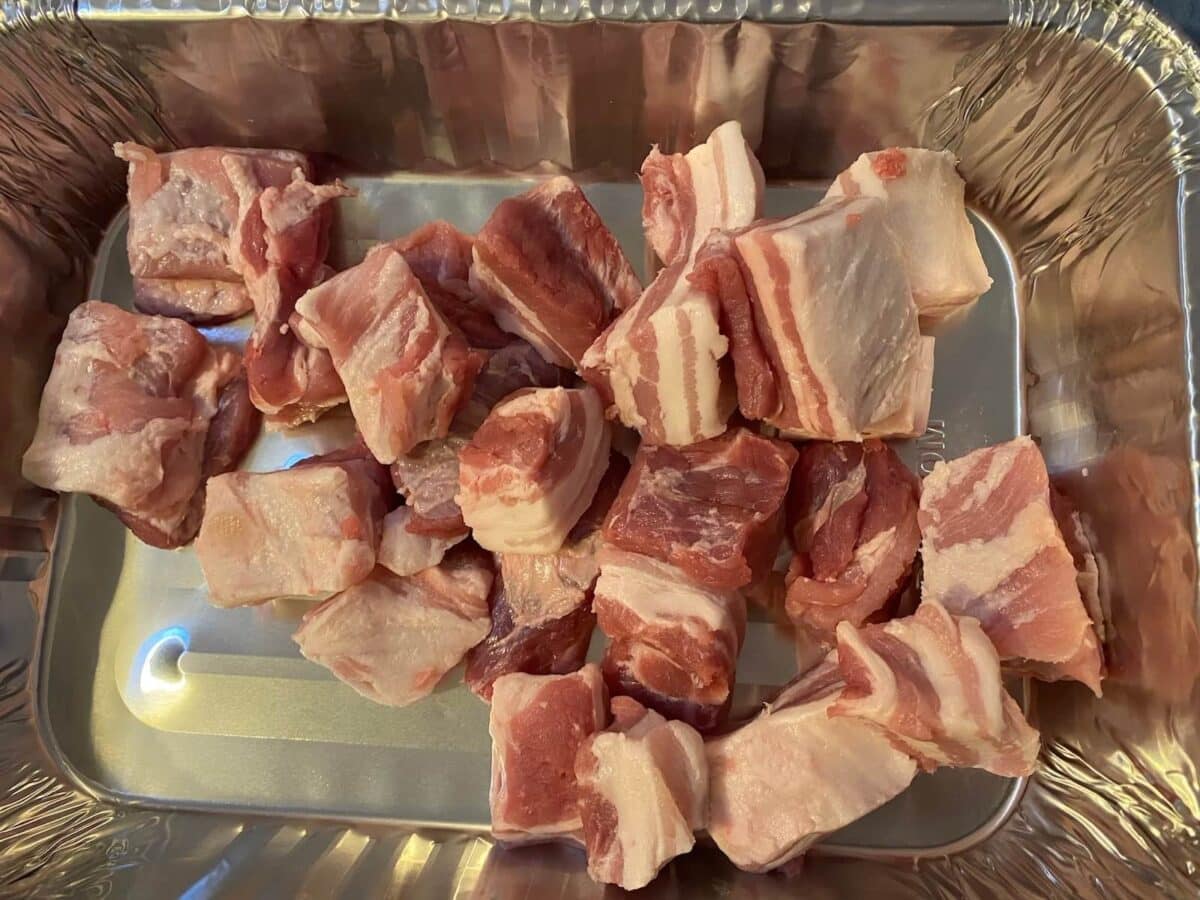 diced pork belly pieces in a foil tray.