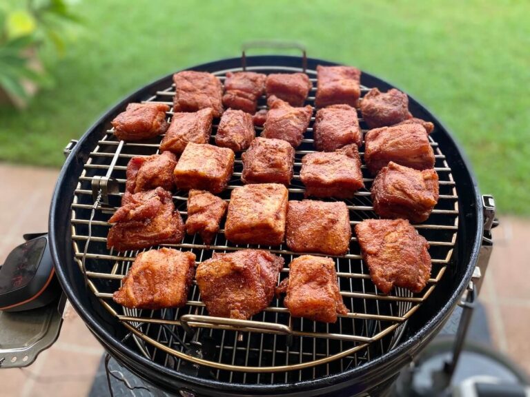 pork belly burnt ends cooking on a bullet smoker in a backyard.