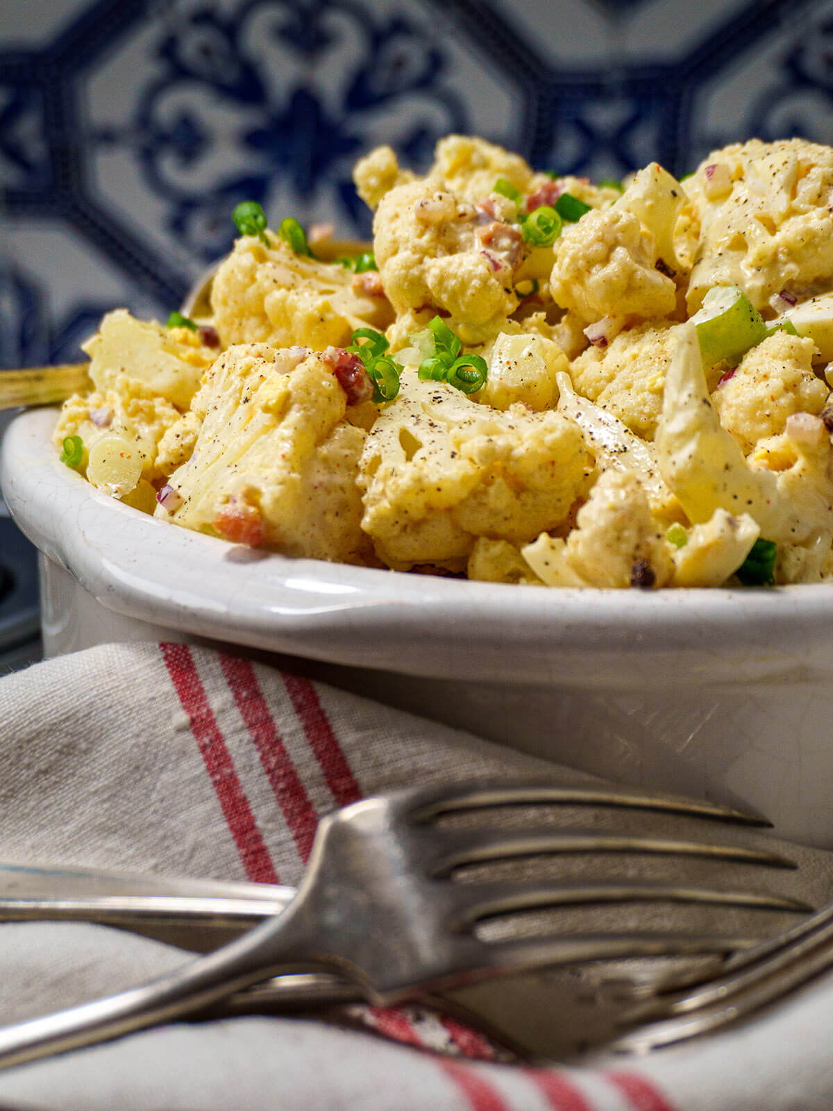 cauliflower potato salad in white serving dish with fork in front.