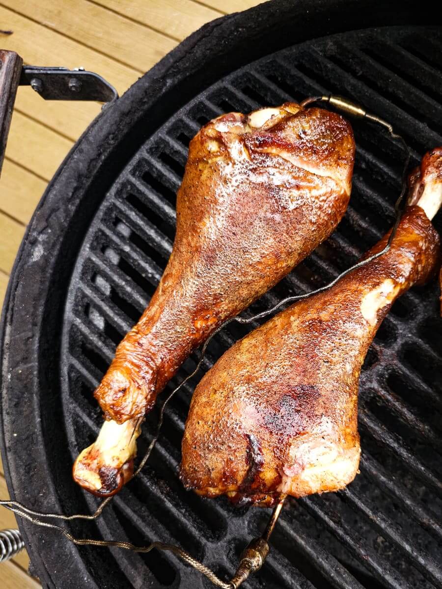 seasoned turkey legs on a smoker grill plate.