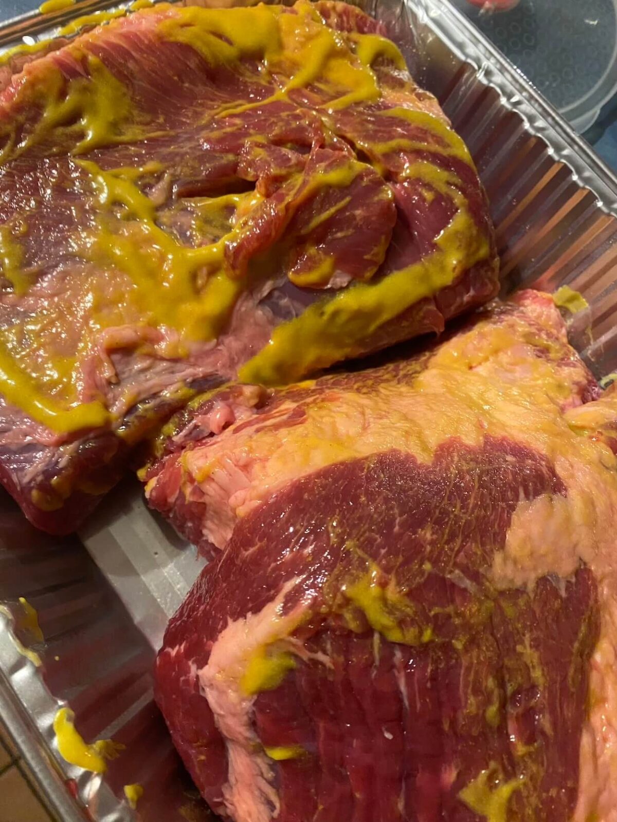 two beef brisket with mustard rubbed on meat surface.