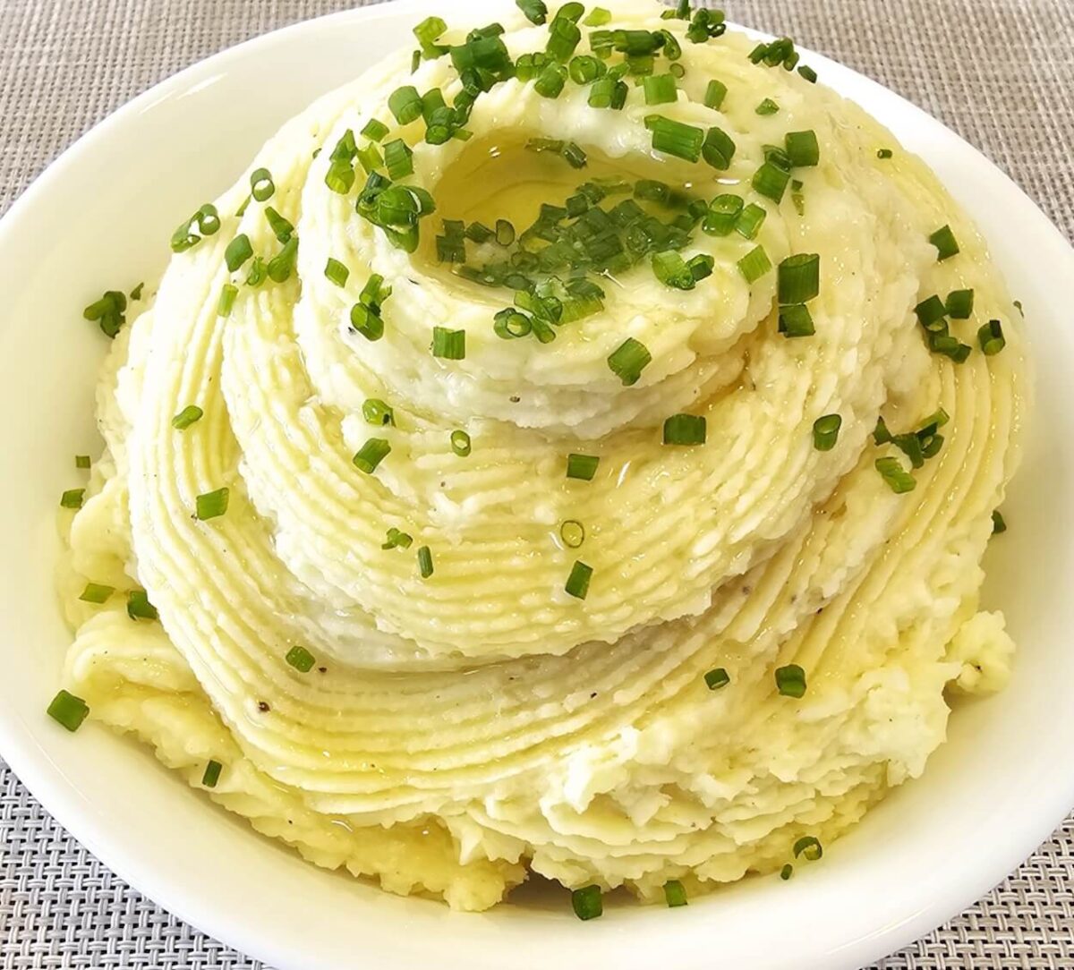pile of mashed potatoes with herbs in a white bowl.