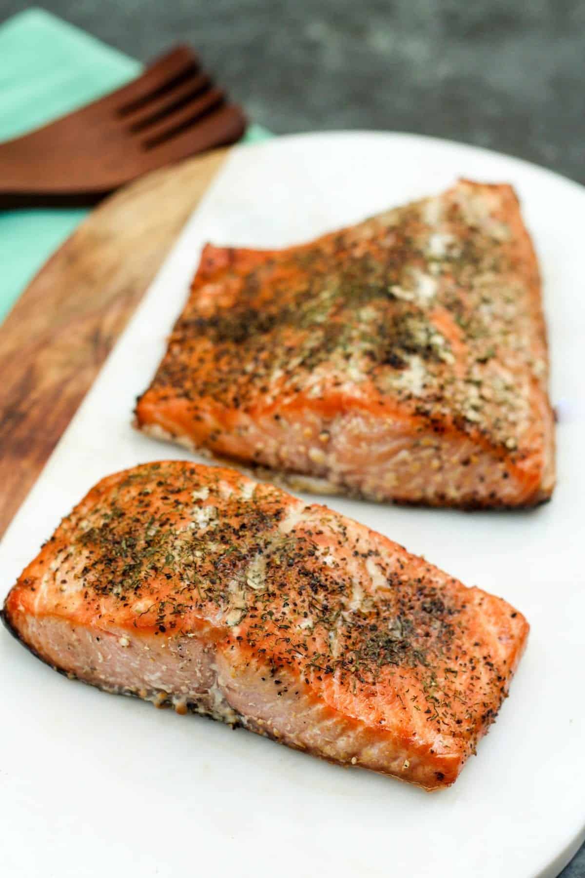 white board with two pieces of seasoned, cooked salmon.