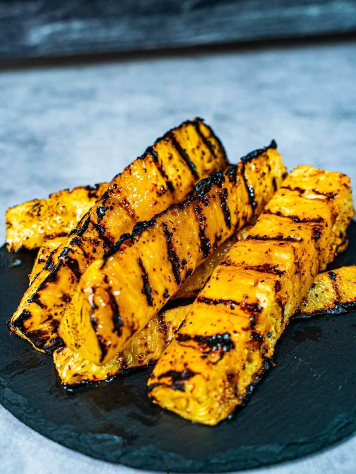slices of grilled pineapple on black tray.