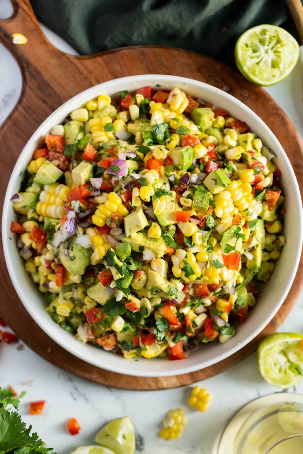 colourful salad in large white bowl with avocado, corn and tomato. 