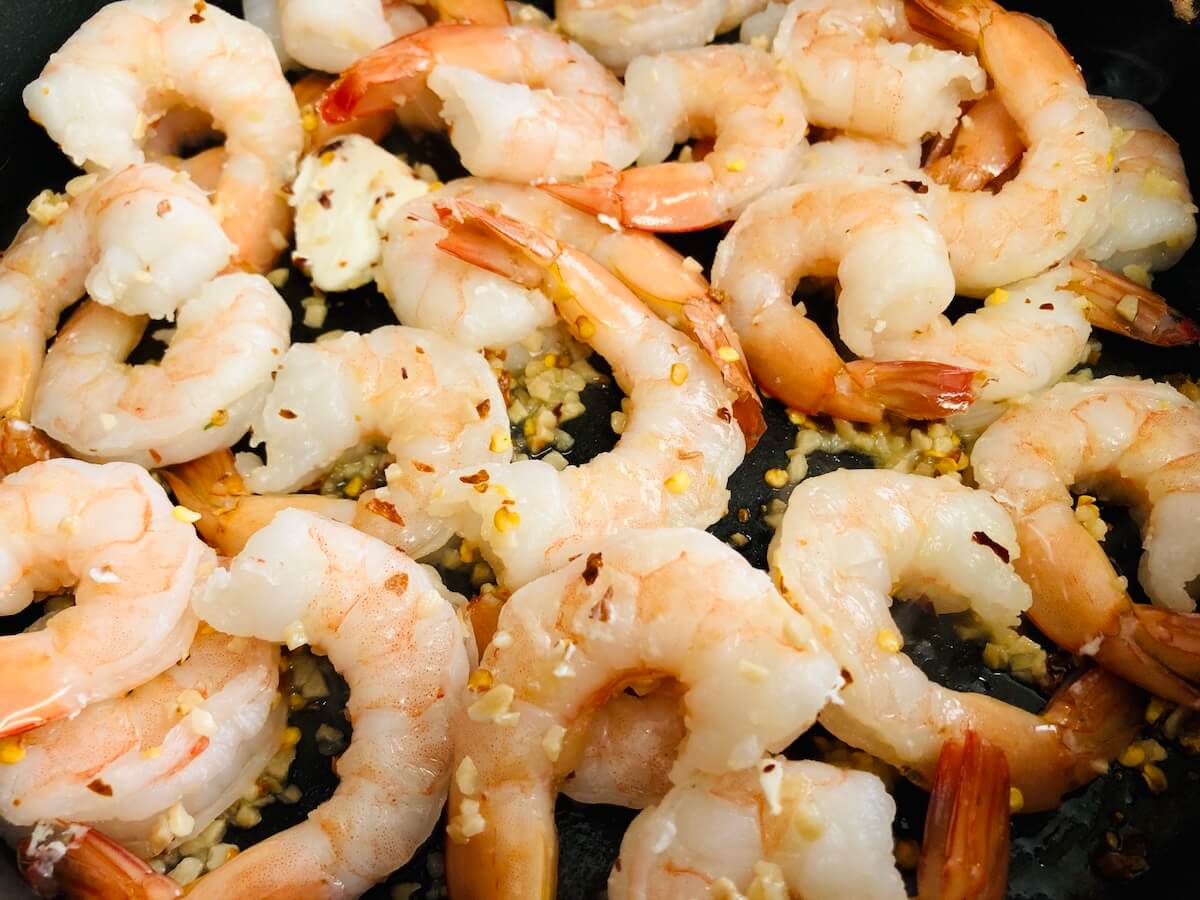 close up of prawns in a skillet with seasoning.