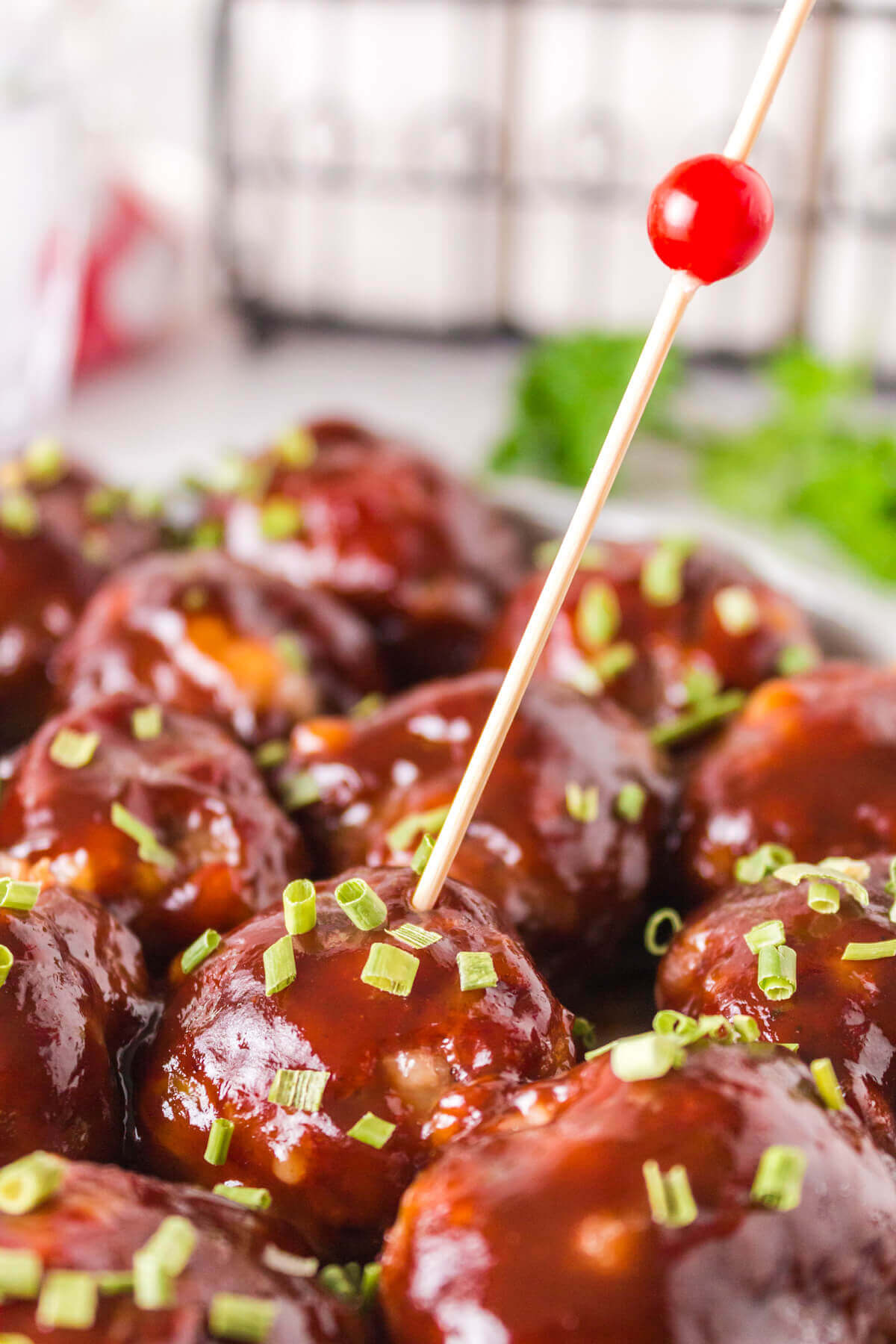 close up of saucy meatballs with a skewer sticking out of one.