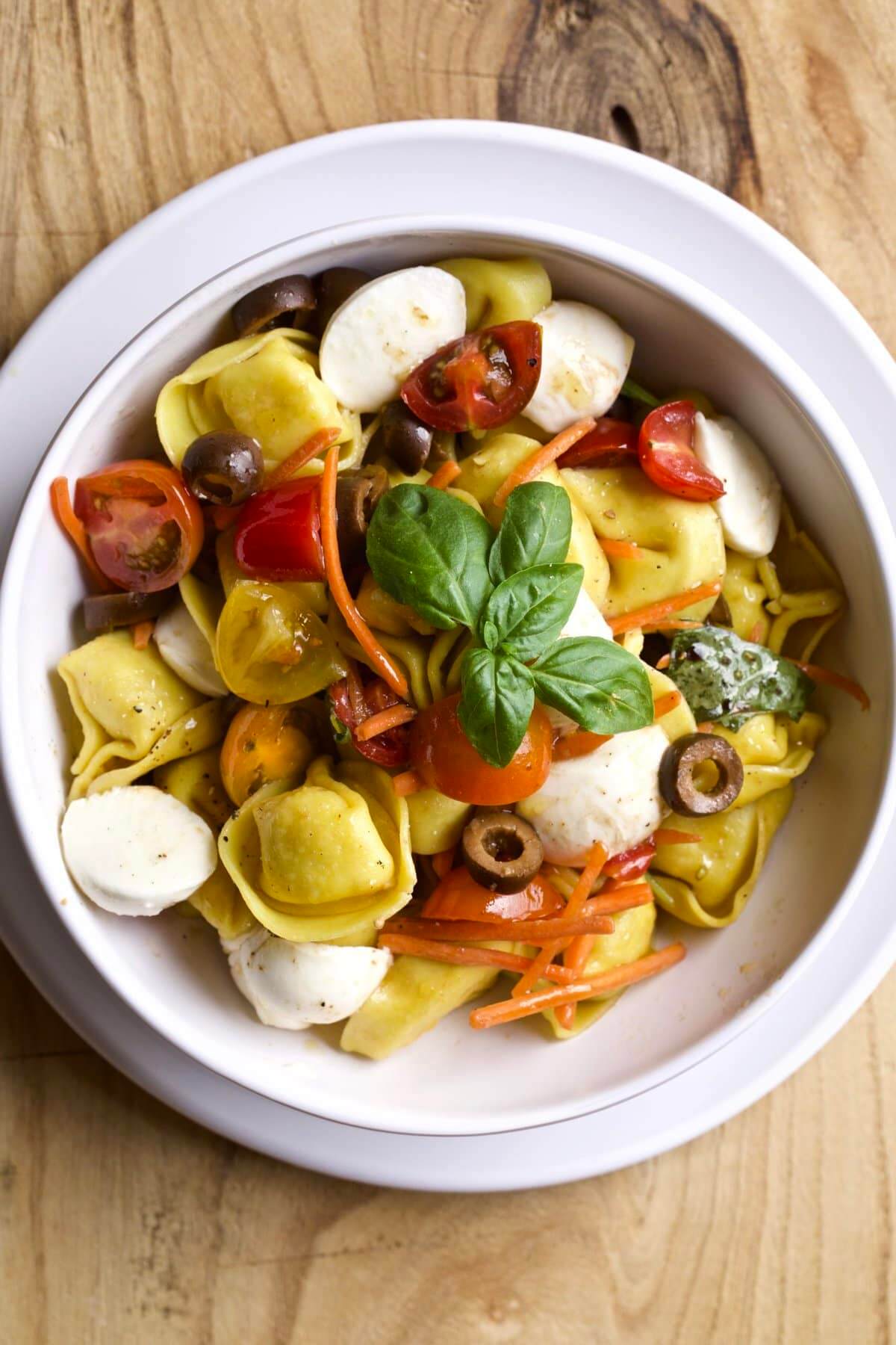 close up of tortellini pasta salad in white bowl.