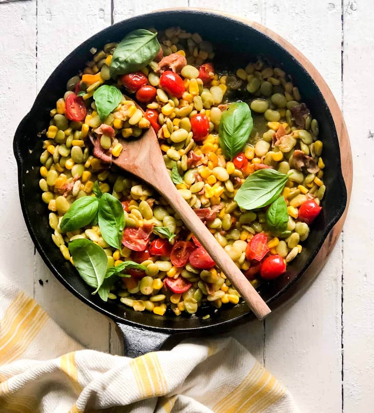 bacon saccotash in a cast iron skillet with a spoon.