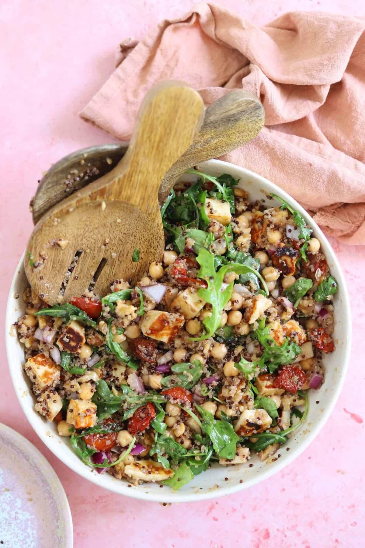 chickpea halloumi salad in a white bowl on pink background.