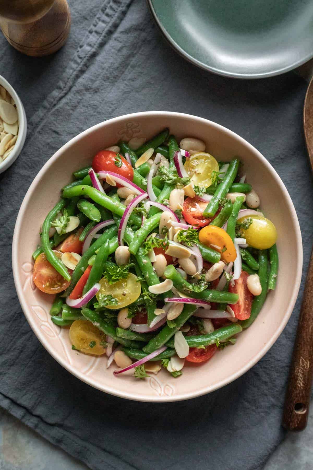 italian green bean salad on a beige plate on a table.