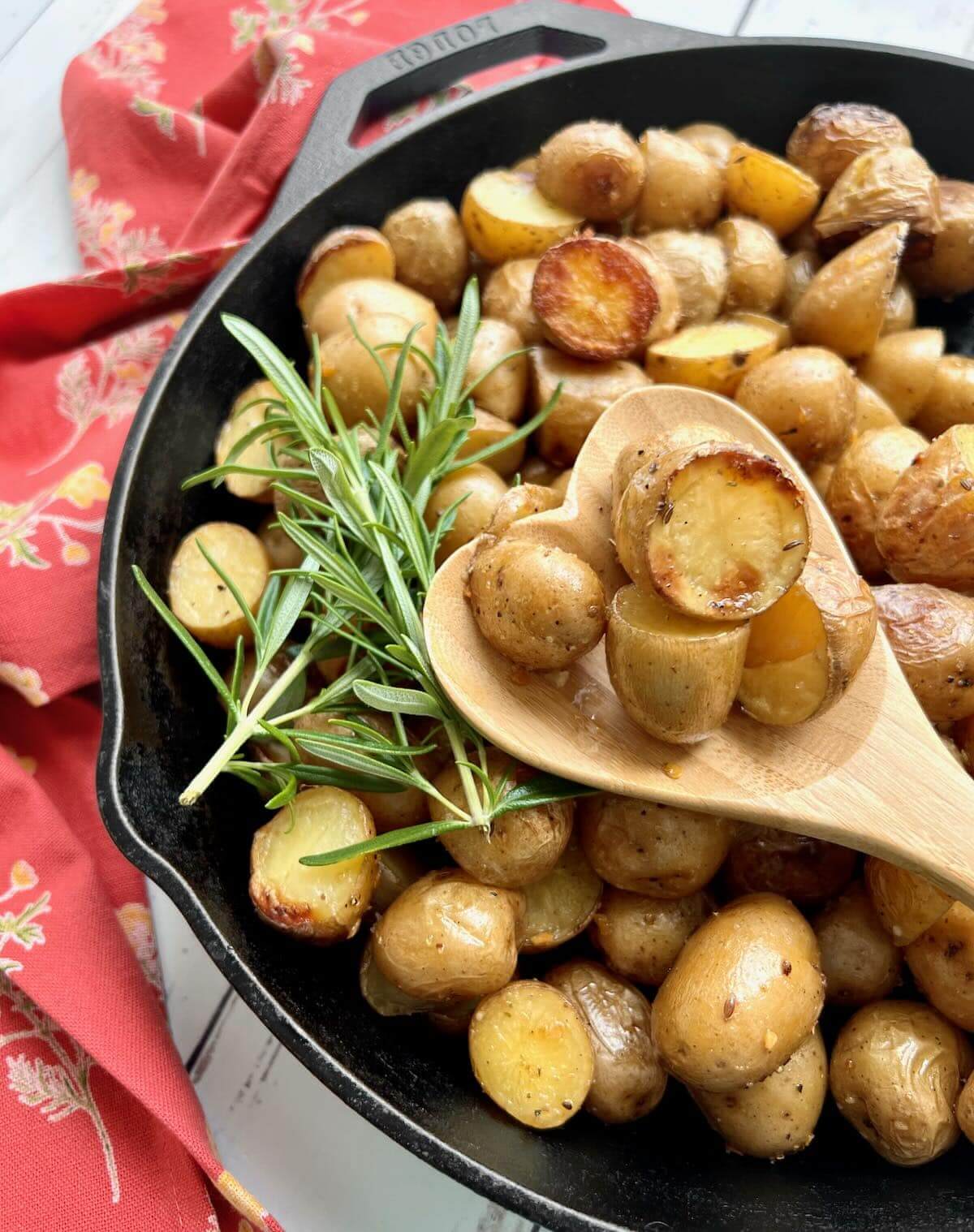 smoked potatoes in a cast iron skillet with a spoon.