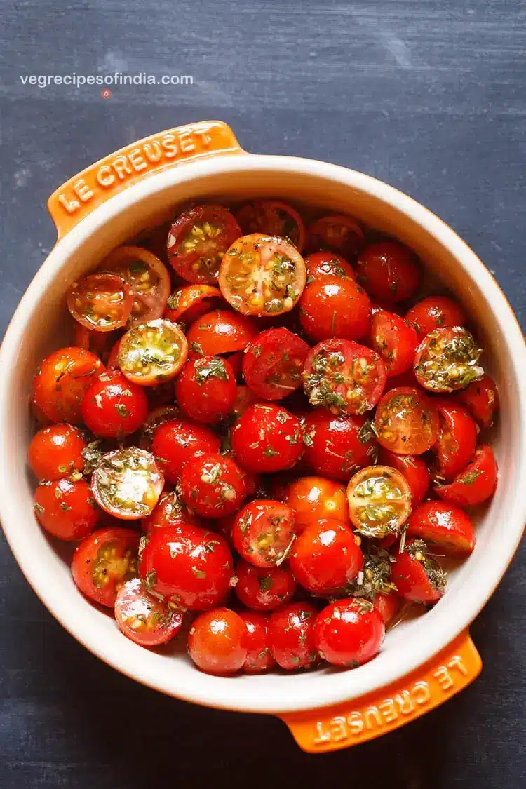 baking dish with cherry tomato salad on blue background.