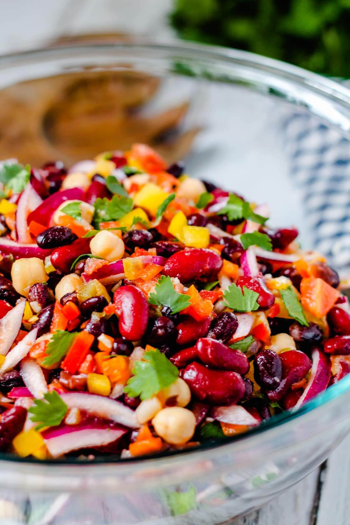 close up of colourful three bean salad in a glass bowl.