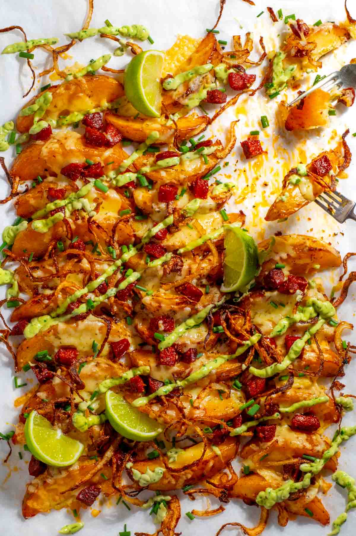 loaded wedges on baking tray with cheese and dressing drizzled over.