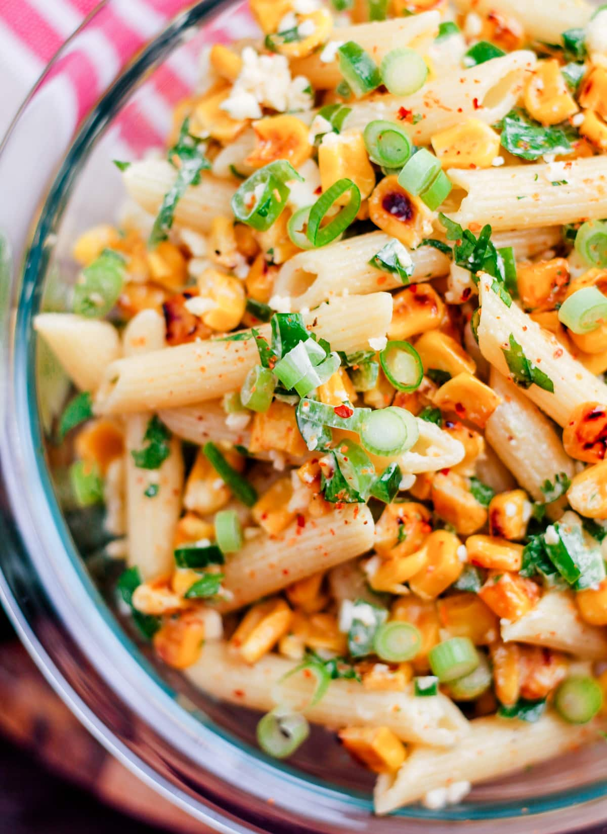 close up of mexcian street corn pasta salad in clear bowl.