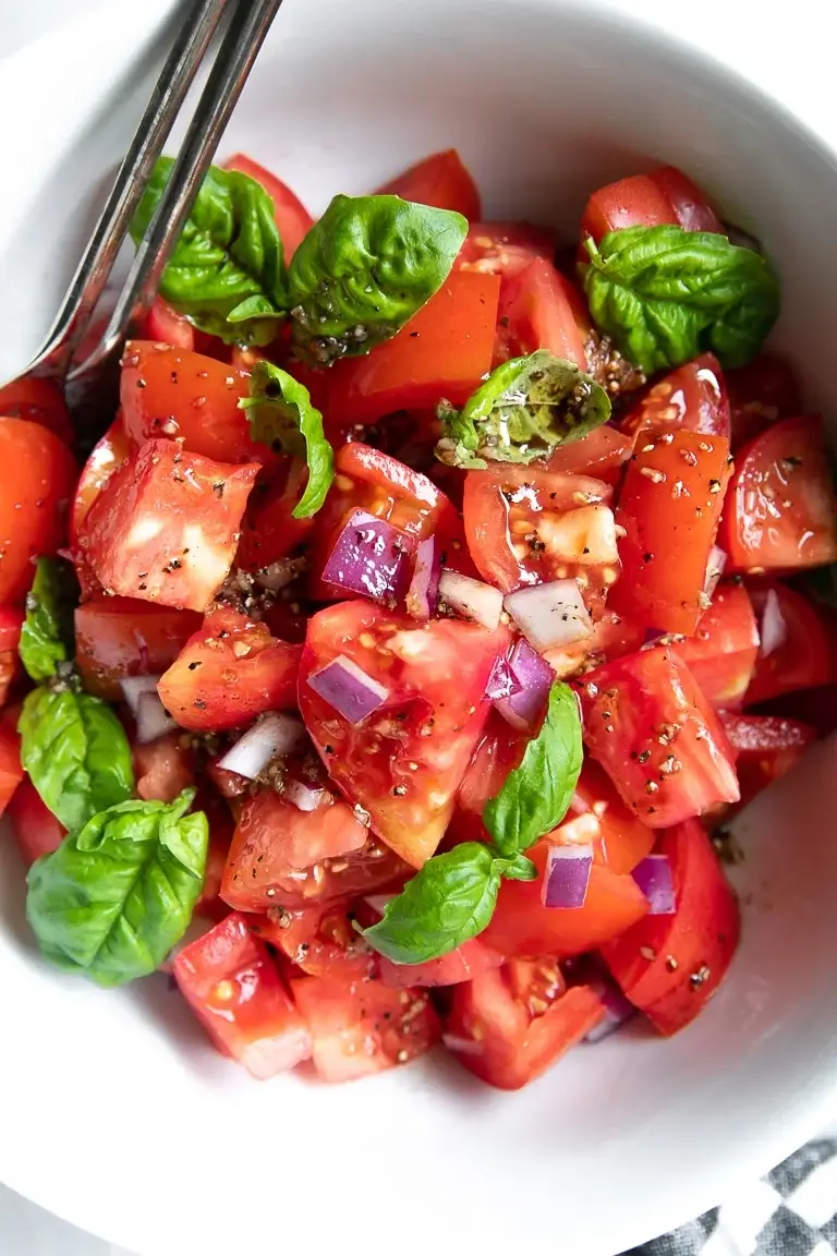 close up of tomato basil salad in a white bowl.