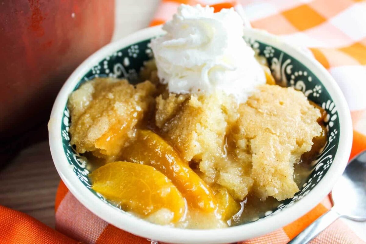 smoked peach cobbler in a bowl with ice cream.