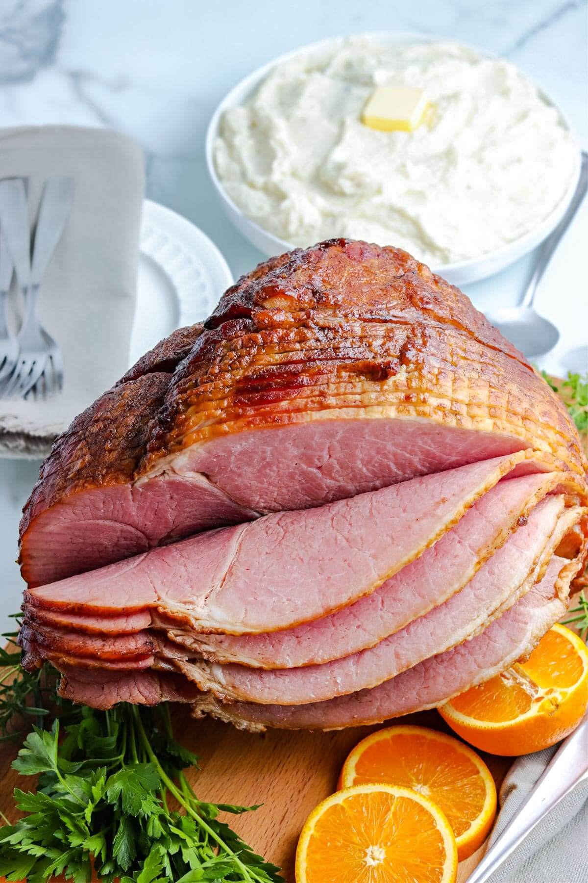 smoked spiral ham, sliced and sitting on bed of orange slices.