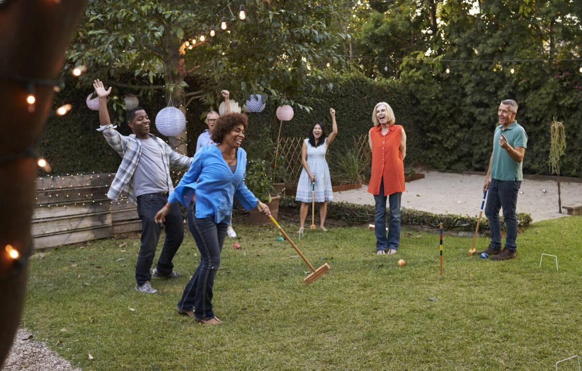 group of friends playing croquet in backyard.