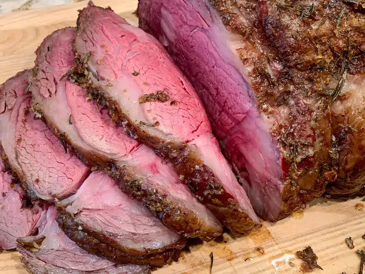 smoked prime rib roast sliced on board.